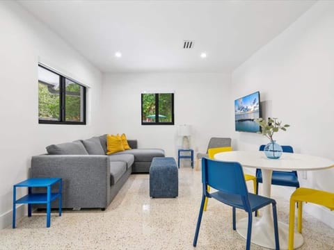 Stylish comfort in Miami, Florida! This modern space features a gray sectional, vibrant dining area, natural light, and sleek concrete floors—perfect for relaxing after exploring nearby beaches and city attractions.