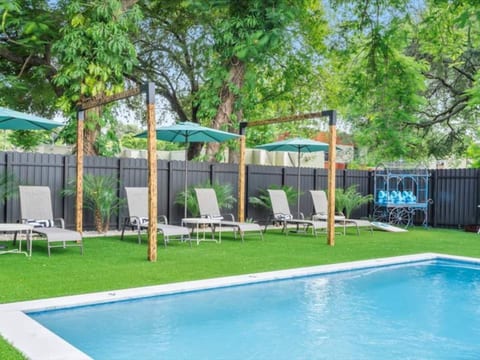 Lush backyard oasis in Miami, Florida, featuring a sparkling pool, manicured lawn, lounge chairs, and shaded pergola — the perfect space to relax, sunbathe, and unwind in privacy.
