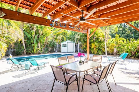 Poolside dining under a stylish pergola in Dania Beach, surrounded by lush greenery.