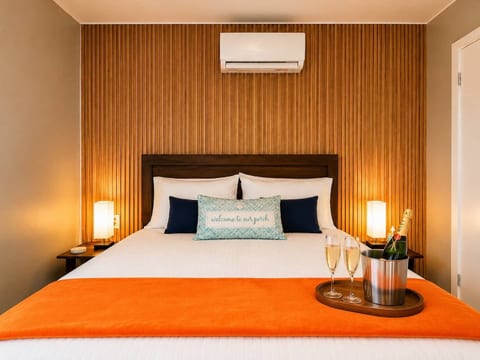 Romantic king bedroom with warm ambient lighting, wood-accent wall & champagne—perfect for a special getaway.