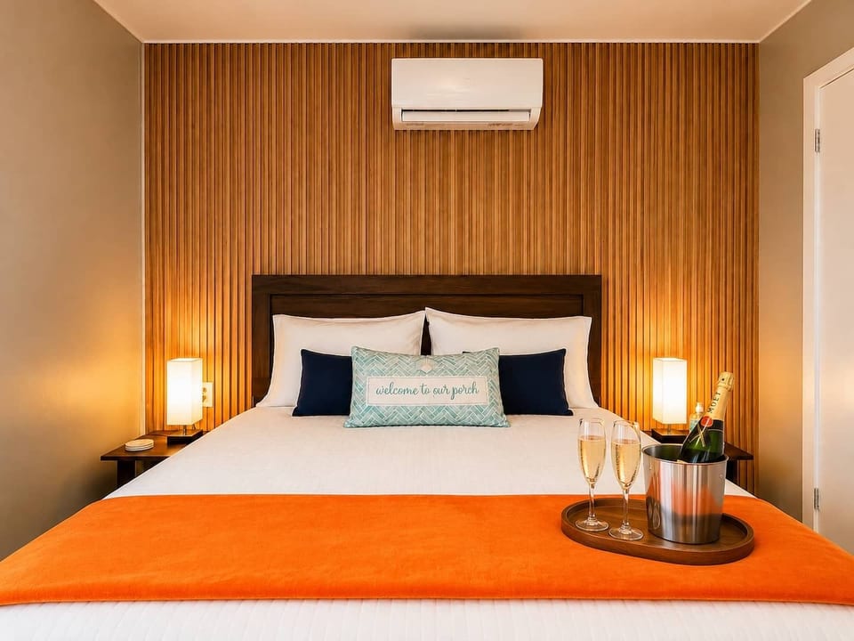 Romantic king bedroom with warm ambient lighting, wood-accent wall & champagne—perfect for a special getaway.