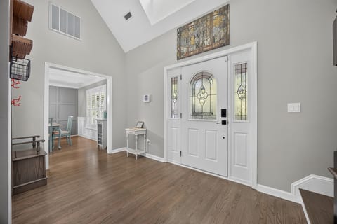 Bright vaulted foyer with stained-glass entry and warm wood floors
