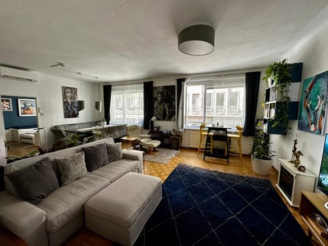 Bright, art-filled living room with large windows and cozy lounge space