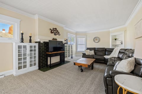 Bright, inviting living space featuring leather sofas, a large TV, and classic charm for comfortable group gatherings.