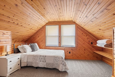 Warm and inviting bedroom with rich wood walls, soft bedding, and a calm atmosphere—perfect for a restful night.