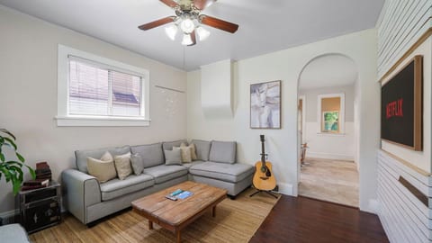 A closer look at the cozy sectional and flat-screen TV. The open arched doorway leads straight into the kitchen, keeping the floor plan connected and social.