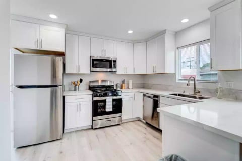 Kitchen with Full Fridge/Freezer, Range Stovetop w/ Oven, Dishwasher, Dining Counter, and Common Area Half-Bath