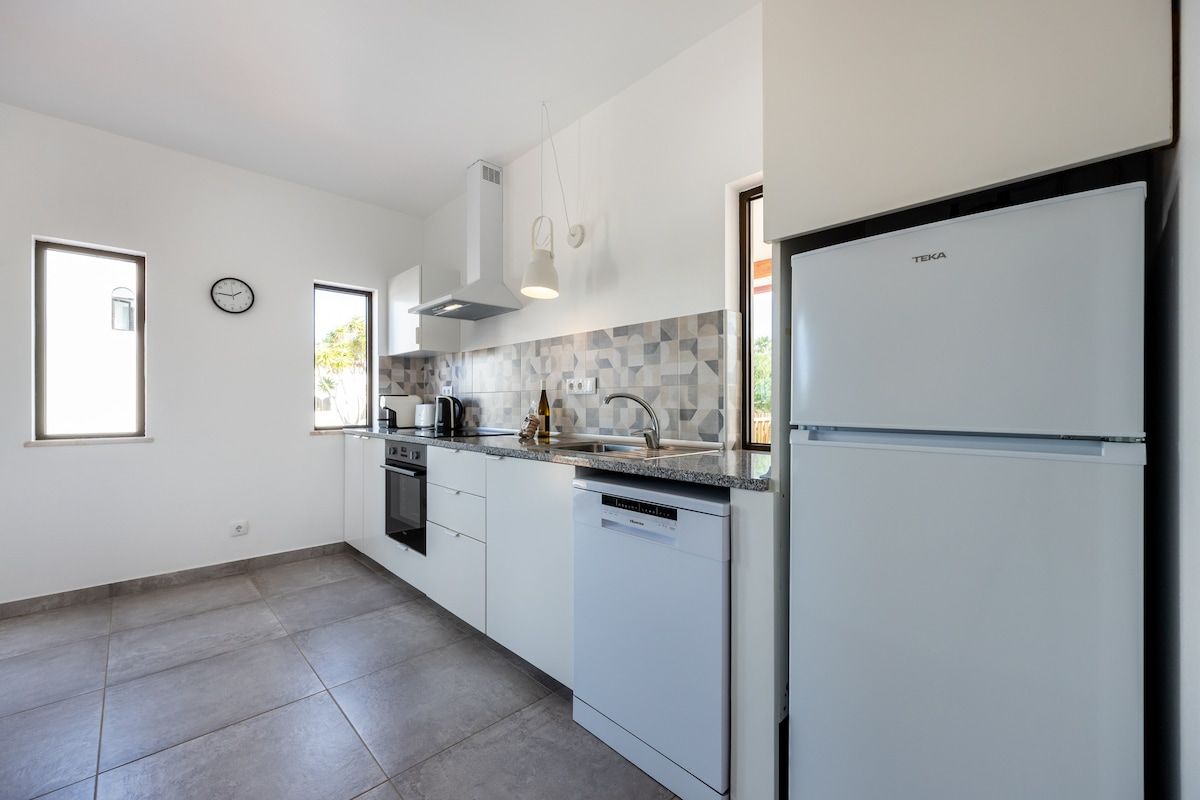 Full kitchen with dishwasher, oven, microwave, refrigerator/freezer, coffee machine, toaster, kettle. Views to the pool and shared garden areas.