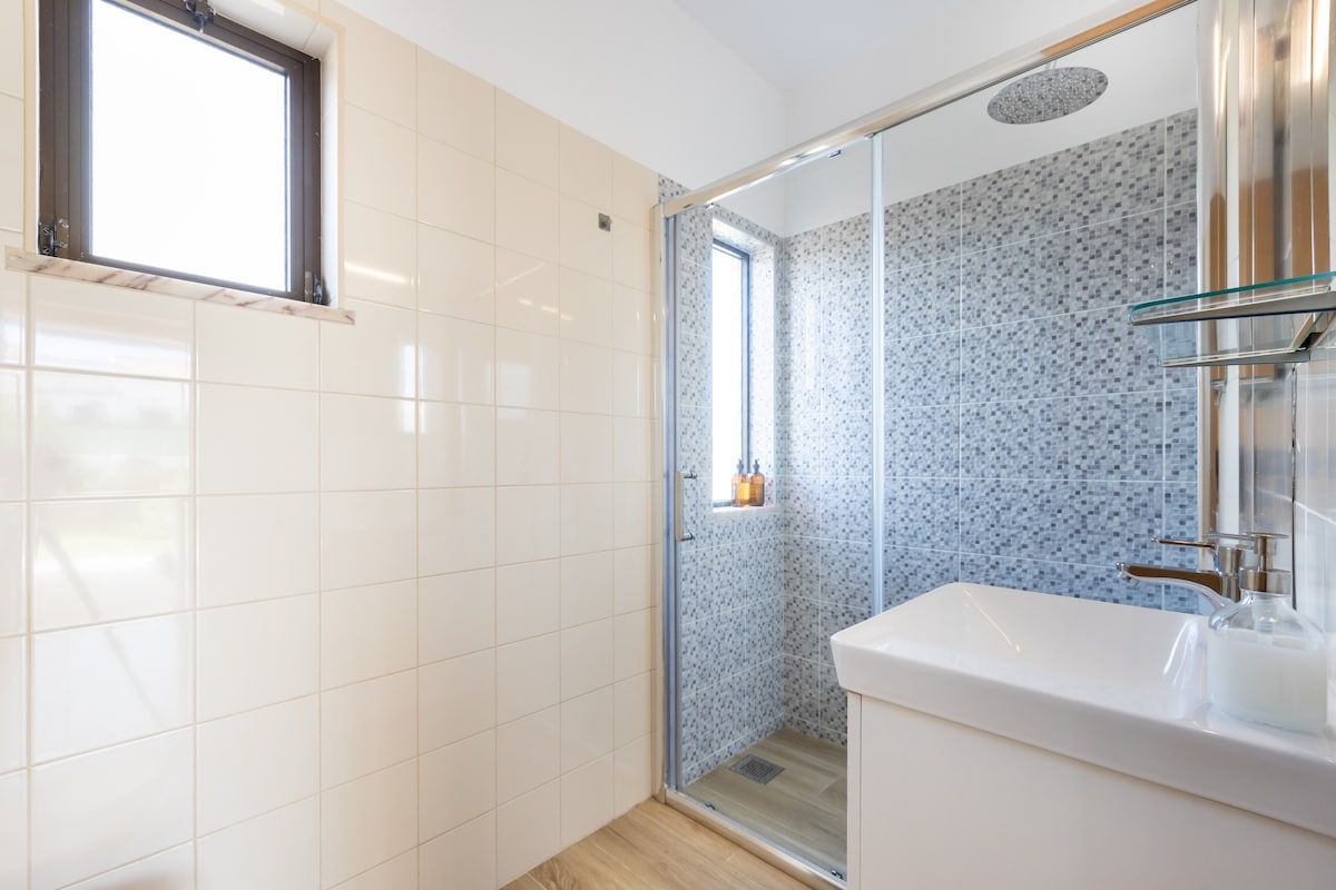 Bathroom with walk-in shower, sink and toilet. Hair dryer provided.