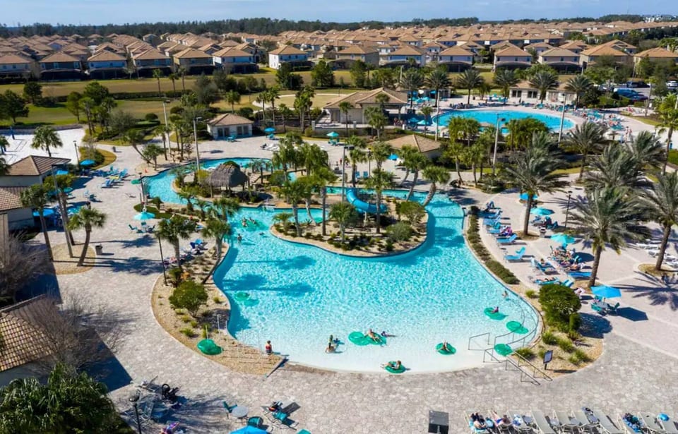 Resort-style pool surrounded by lush palms & vibrant loungers—dive into fun!