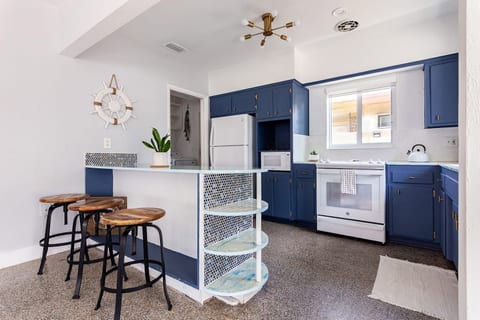 Coastal vibes in Hollywood, Florida! This charming kitchen with blue-white cabinetry, mosaic breakfast bar & ship wheel décor is perfect for long-term guests, couples, or families seeking a stylish, beach-inspired space to cook, dine & relax.