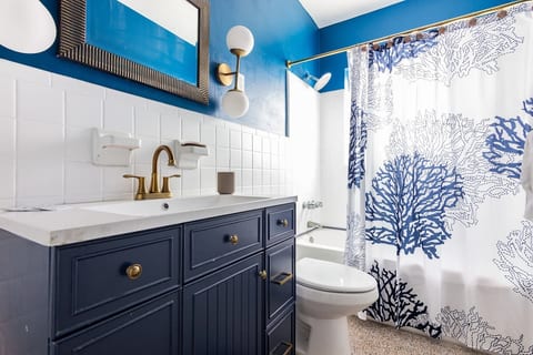 Splash of style in Hollywood, Florida! This vibrant bathroom with navy vanity, coral reef shower curtain & coastal accents is perfect for couples, solo travelers, or long-term guests seeking a fresh, ocean-inspired retreat.