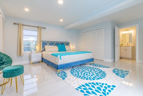 This serene bedroom features a plush blue-and-white bed, gold-accented nightstands, and a rug.
