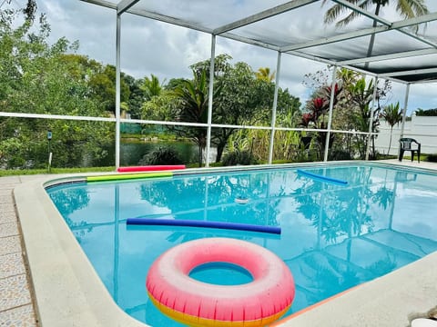 This screened pool with tropical views & colorful floats is perfect for families seeking fun.