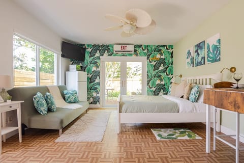 Escape to Hollywood, Florida! This vibrant tropical suite features a cozy bed, stylish lounge, smart TV, fridge, and lush decor—perfect for beach lovers and long stays. Natural light and outdoor access make it a sunny retreat.