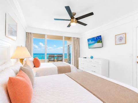 Second bedroom with cozy beds, ocean views, and a flat-screen TV—perfect for families or groups.