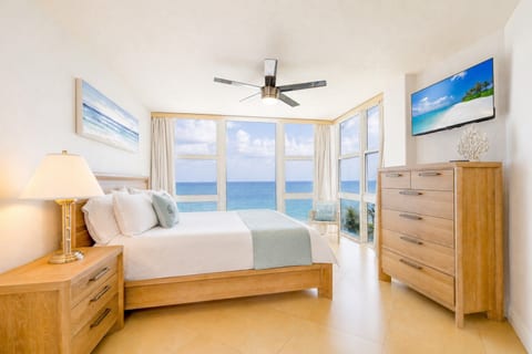 Master bedroom with a king bed, ocean views, a ceiling fan, and a flat-screen TV.