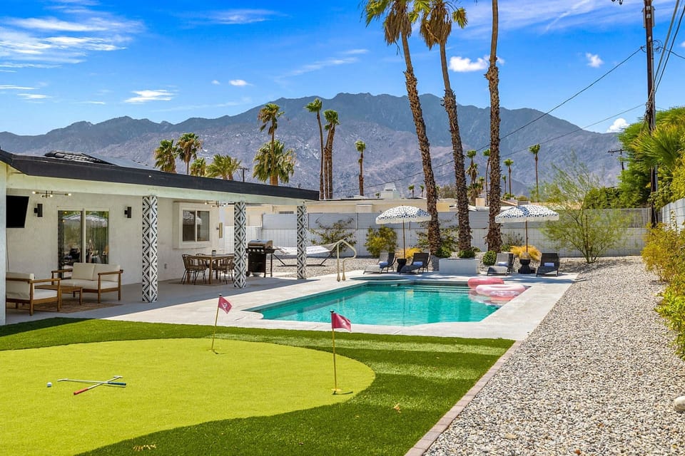 Sun-soaked pool & patio framed by palms and mountain backdrops, setting the scene for laid-back desert days.