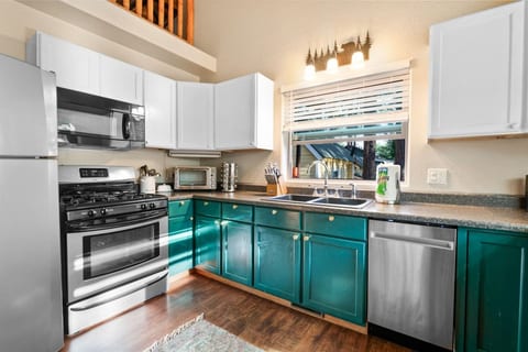 Modern kitchen w/ teal cabinets, full appliances, & plenty of counter space for easy meals.