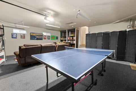 Spacious game room featuring a ping-pong table & lounge seating for friendly competition.
