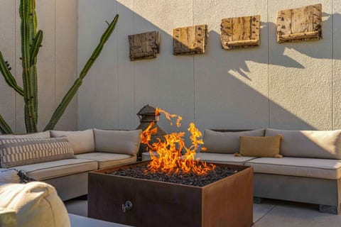 Outdoor lounge w/ gas fire table, cushioned sectional & rustic wood wall art for cool desert nights.