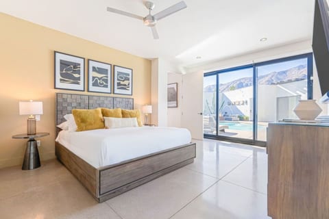 Bedroom w/ king bed, framed desert art & sliding doors opening to the pool and mountain views.