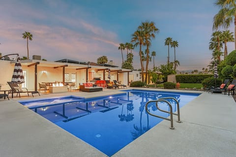 Evening poolside glow w/ palm trees, lounge seating, and a warm outdoor living area made for relaxing after sunset.