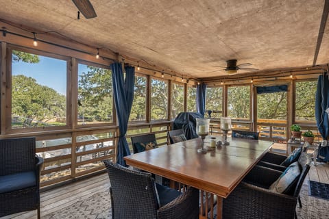 Covered porch w/ outdoor dining & lounge seating, surrounded by trees for a peaceful feel.