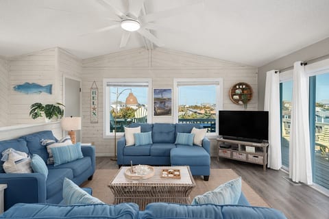 Bright living room w/ comfy seating, TV & large windows letting in plenty of natural light