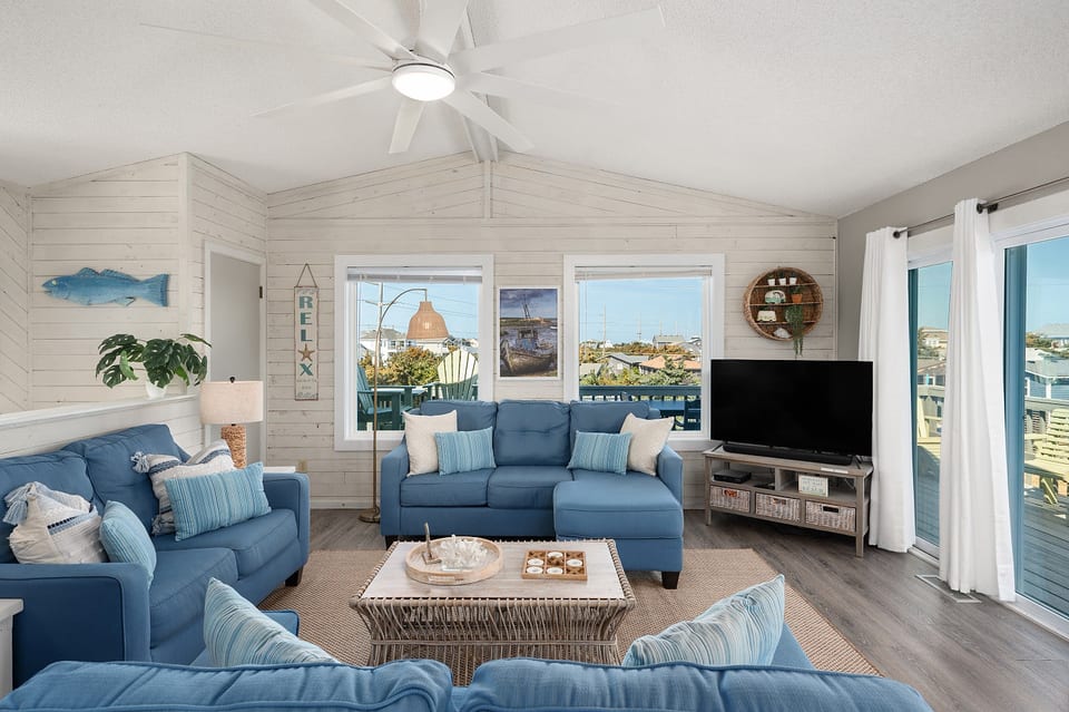 Bright living room w/ comfy seating, TV & large windows letting in plenty of natural light