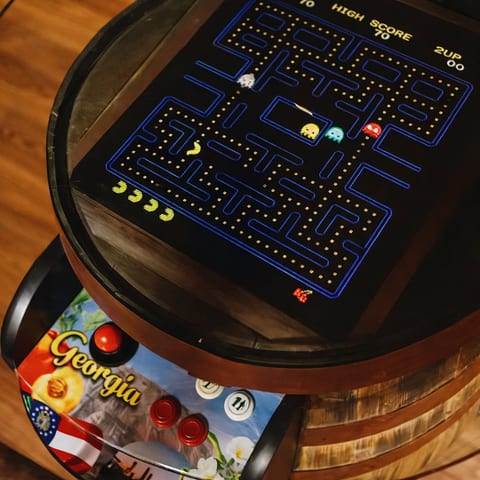 Fun meets cozy in the living room, featuring a custom whiskey barrel arcade with classic games, Smart TV, and a curated collection of board and card games. The perfect space for playful nights, friendly competition, and relaxed entertainment