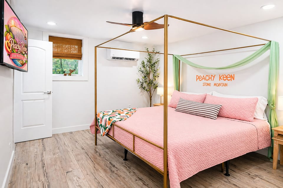 Primary Bedroom 1 features a luxe canopy king bed with memory-foam mattress, USB bedside lamps, 55” smart TV, walk-in closet, and a spa-style ensuite with double vanity, soaker tub, and rainfall shower—your private retreat for rest and relaxation.