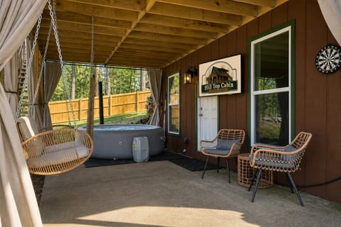 Covered patio with hot tub, swing chair, and cozy cabin-style seating