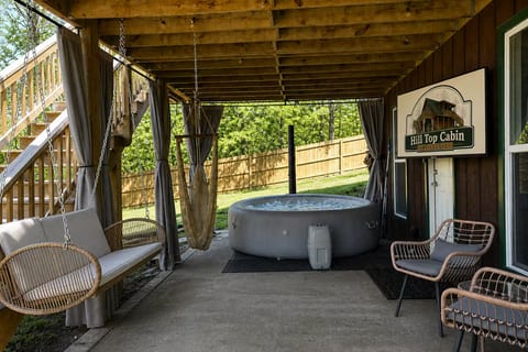 Covered patio with private hot tub, lounge swings, and cozy cabin charm