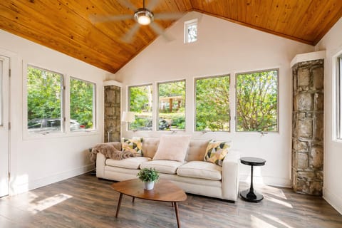 Sunlit lounge with vaulted wood ceiling, big windows, and garden views