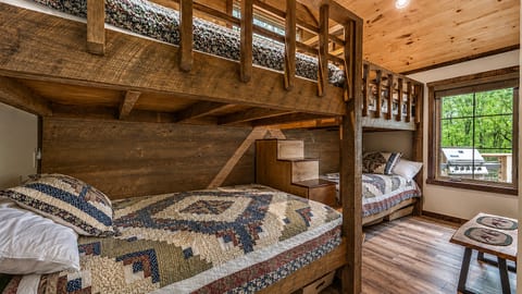 Rustic bunk room with built-in beds, warm wood finishes, and forest views