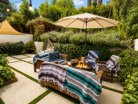 Cozy garden patio with fire pit, lounge seating, and lush private greenery