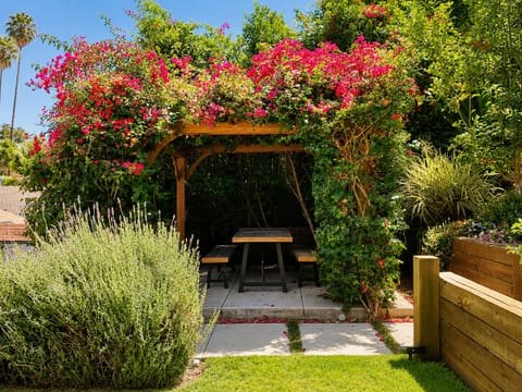 Private garden pergola with shaded outdoor dining and lush blooms