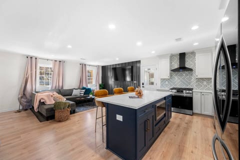 Experience open concept living with a seamless flow from the living room featuring a Smart TV to the kitchen and dining area. Enjoy cooking and dining with essentials and an eat-in island for 3, plus a designated dining table for 4.