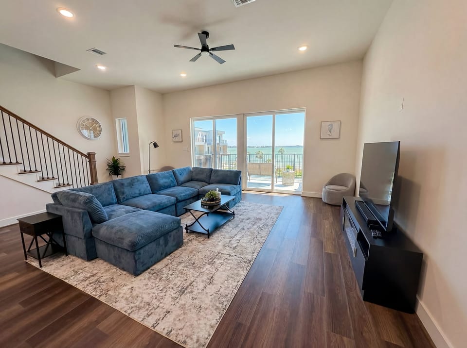 Bright waterfront living room with large sectional and balcony views