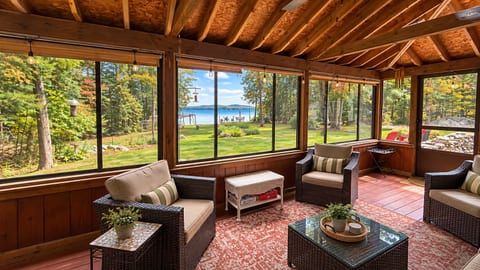 A cozy screened-in porch with comfortable seating and peaceful lake views.