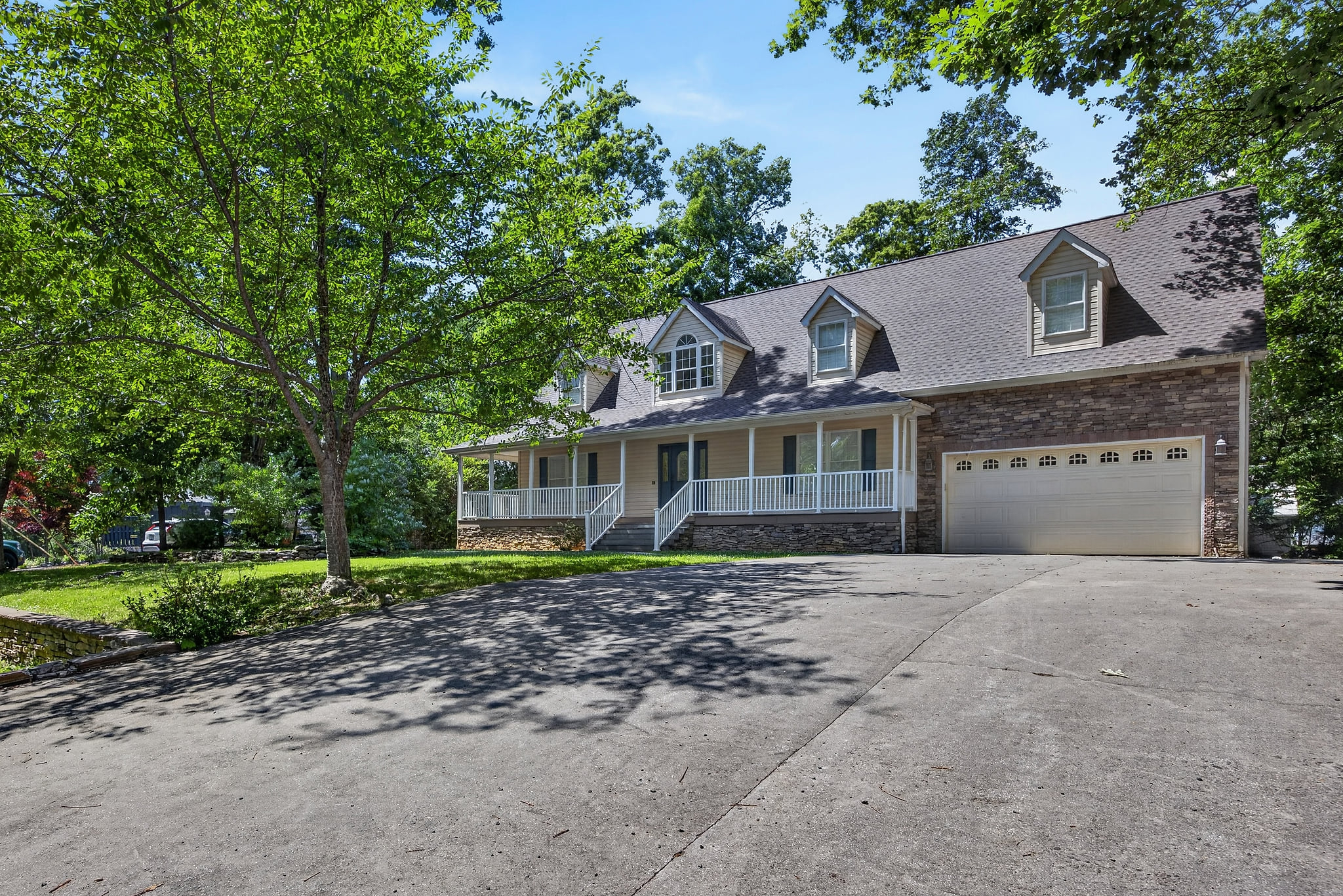 Spacious home with private driveway, garage, porch, and wooded setting