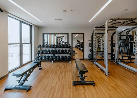 Bright modern fitness room with free weights, benches, and strength equipment