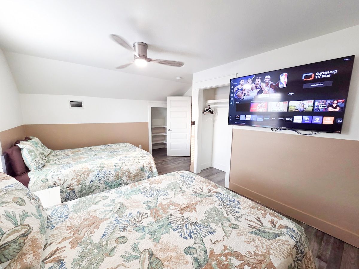 4th Bedroom with two Queens size memory foam mattresses, 65" Samsung Smart TV, Night stand w/power strips for hungry phone chargers, ample closet space and window view of pool.