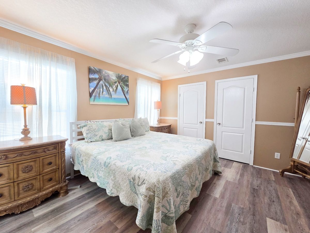 Master Bedroom with King Size Bed, ceiling fan, night stands with lamps and power strips for electronic devices, and a 55" Samsung Smart TV w/ rear LED lighting.