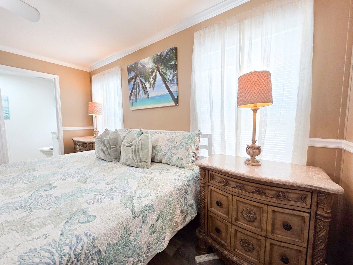 Master Bedroom with King Size Bed, ceiling fan, night stands with lamps and power strips for electronic devices, and a 55" Samsung Smart TV w/ rear LED lighting.