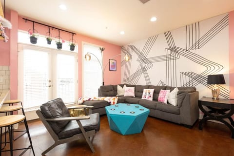 A modern twist on cowgirl glam! This space features a bold accent wall, a huge sectional sofa, and a funky turquoise gem-shaped coffee table. The perfect backdrop for selfies, games, or movie nights.