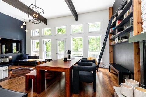 Spacious living room featuring a long dining table, library wall, and modern design