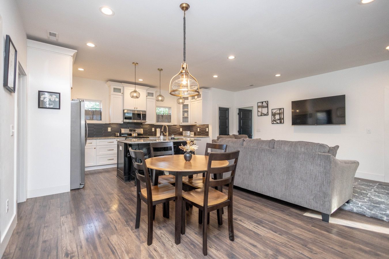 Welcome to the bright and spacious open-concept heart of the home! This view shows the dining area, cozy living room with a large couch, and the modern kitchen island.