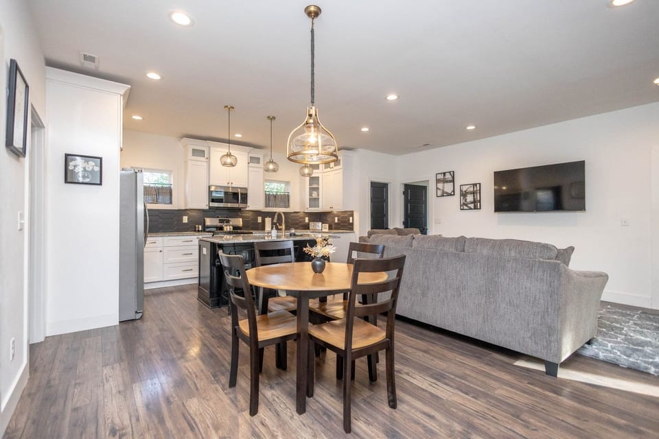 Welcome to the bright and spacious open-concept heart of the home! This view shows the dining area, cozy living room with a large couch, and the modern kitchen island.